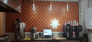 Imagen de la pared de la tienda con logos donde se ve la maquina de café el tpv y luna de las chocolateras