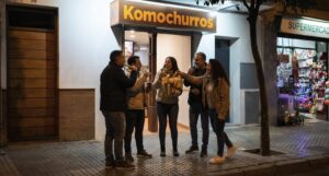 Chicos en la puerta de Komochurros tomando chocolate con churros
